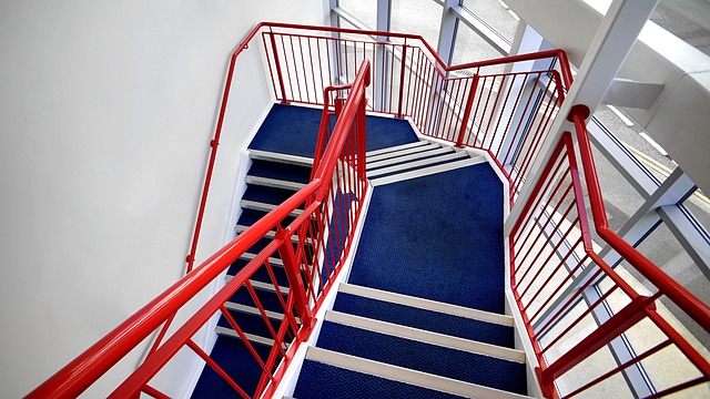 schodiště s modrým kobercem a červeným kovovým zábradlím