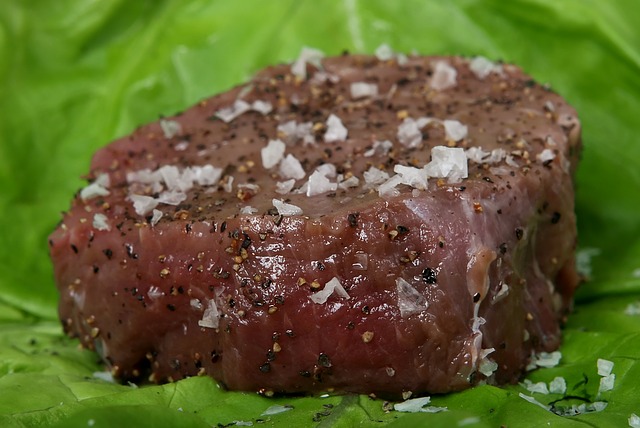 Hovězí syrový steak, posypaný pepřem a solí