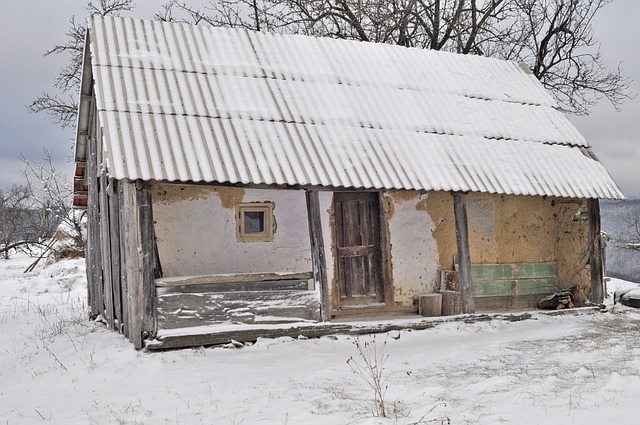 starý domeček, otlučená žlutá omítka, stojí v zimě zasněžený.jpg